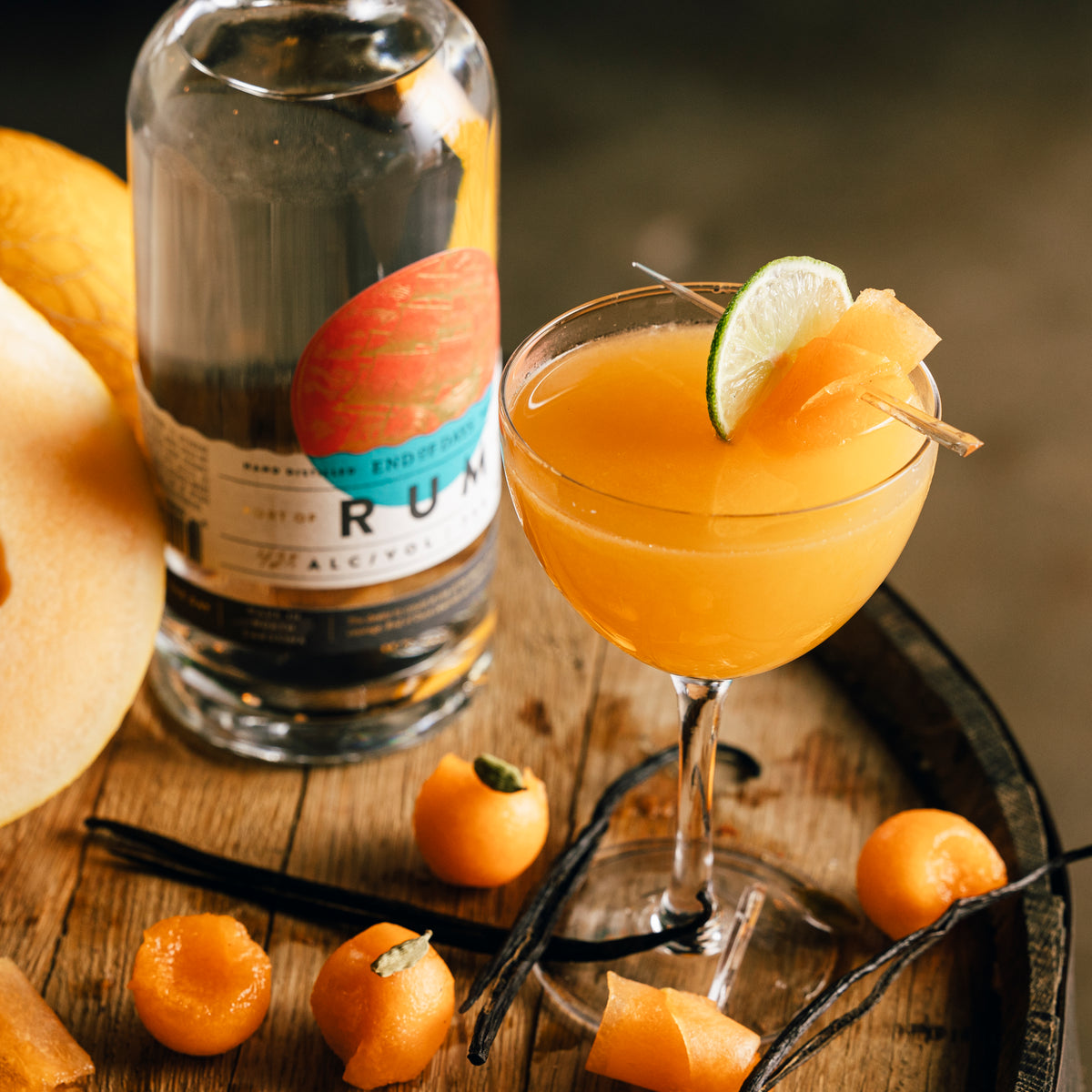 Port of Entry Rum bottle with a peach cocktail on an oak barrel