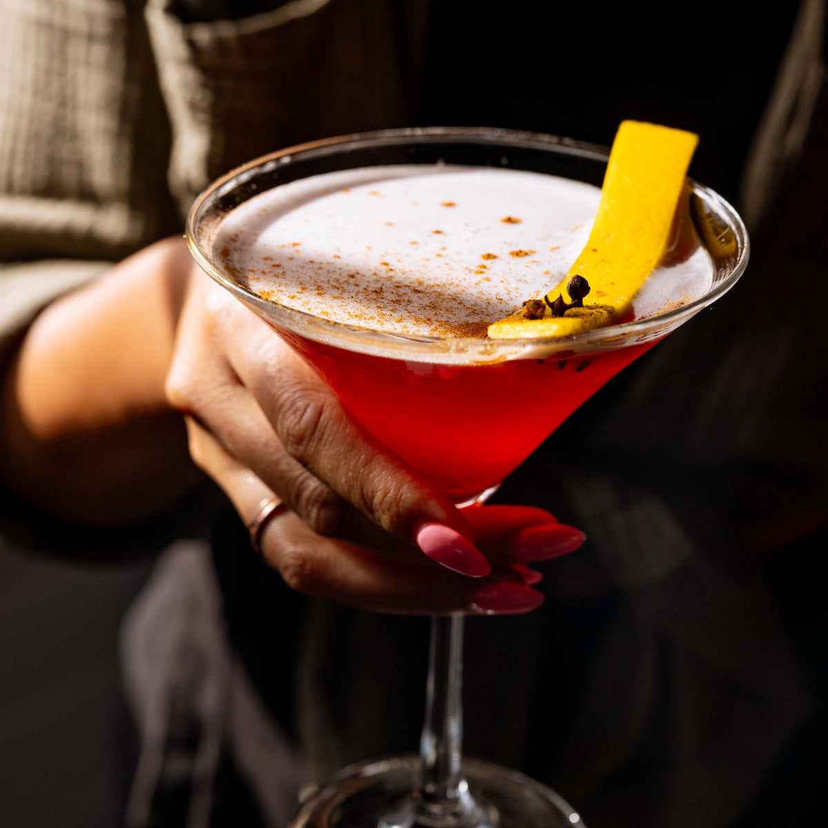 Hand holding a red martini made with Port of Entry Vodka